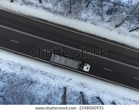 Truck in motion on road in winter, top view of road with truck blurred by traffic