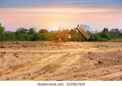 A truck is moving into sand at a ground leveling construction site., land plot for housing construction project with car tire print in rural area Land for sales landscape concept. - Shutterstock ID 2135817629