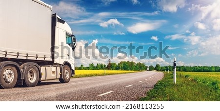 Truck moving on the asphalt country highway in sunny day in spring. Concept of logistic and freight transportation.