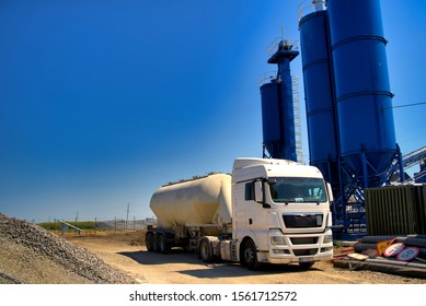 The truck near the concrete station. Asphalt production, Road construction. Blue sky background. Selective focus. Modern station.