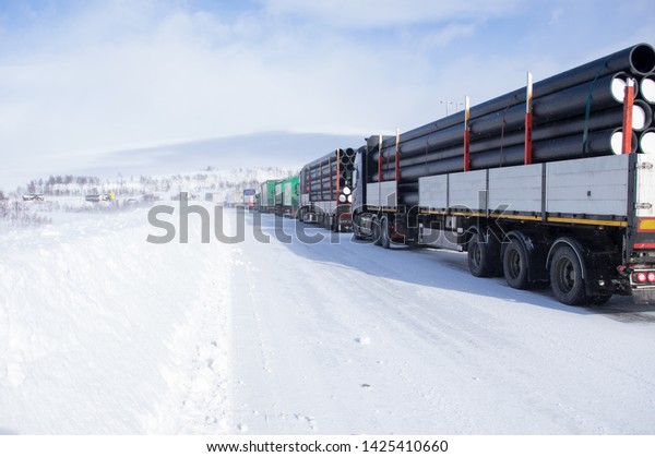 Truck on the Arctic road in\
gloomy weather Heavy snow, a beautiful road in Norway Logistics\
concept
