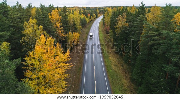 Truck on a autumn color road, aerial, drone\
shot, of a vehicle on a route, in middle of fall forest, dark,\
cloudy, fall day, in\
Scandinavia