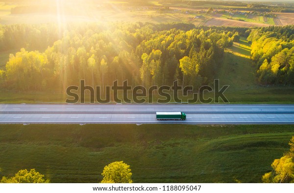 Truck on highway. Truck moving on road in evening.\
Cargo transportation background. Cargo shipping. Road with truck in\
sunlight and sun rays.