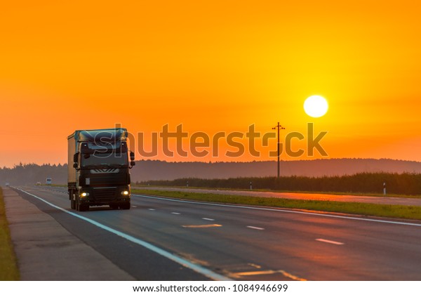truck on the highway in the rays of the rising sun\
at dawn