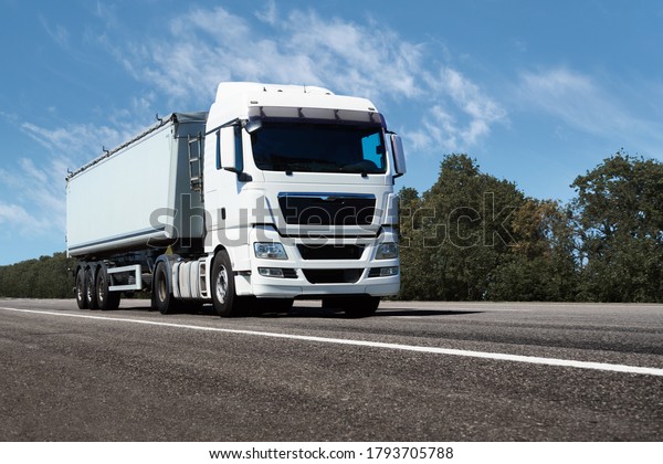 truck on the\
road, front view, empty space on a white container - concept of\
cargo transportation, trucking\
industry