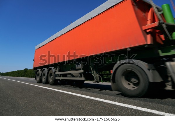 truck on the\
road, side view, empty space on a red container - concept of cargo\
transportation, trucking\
industry
