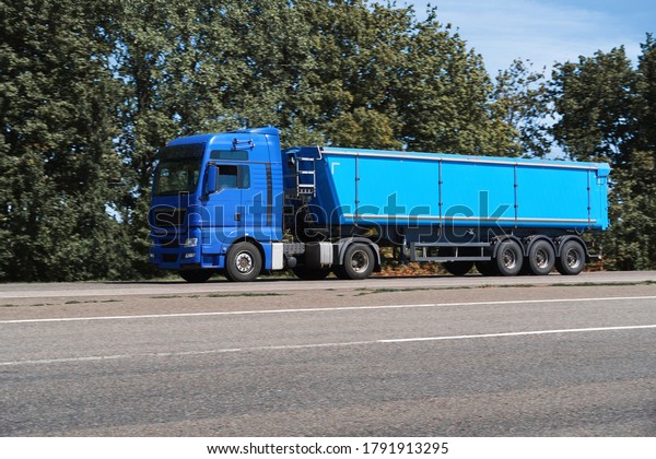 truck on the\
road, side view, empty space on a blue container - concept of cargo\
transportation, trucking\
industry