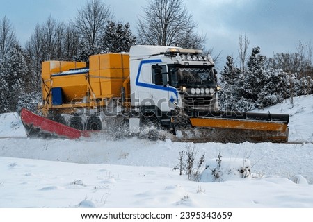 Truck plowing snow and putting salt on road