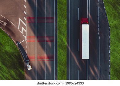 A Truck With A Red Cab And A White Trailer Drives On The Highway, Delivering Goods. The Concept Of Logistics And Transportation Of Goods. Overhead Drone Shot.