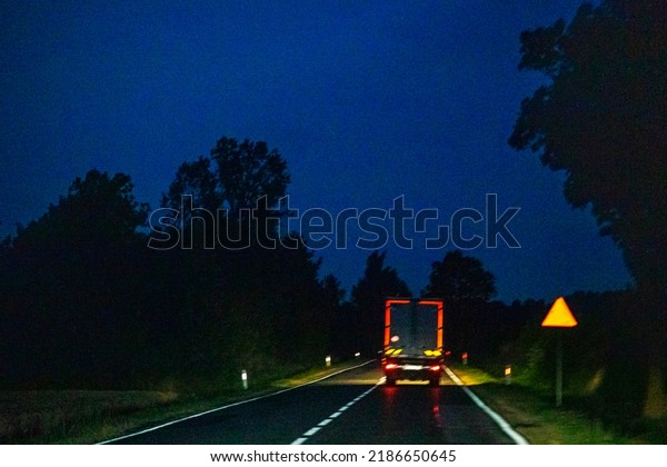 truck with red stops rides on a wet slippery\
European road at night\
