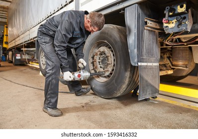 Truck Repair Service. Mechanic Works With Tire In Truck Workshop