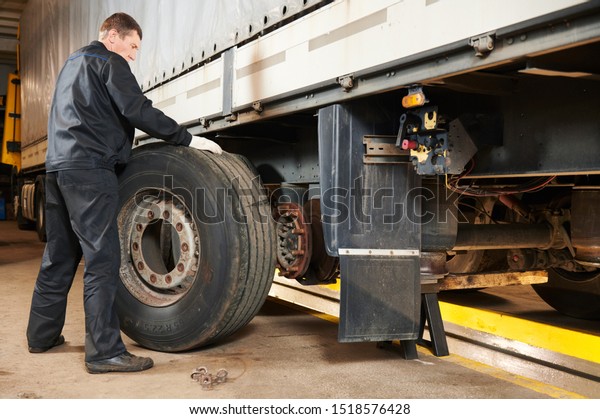 Truck repair service. Mechanic works with tire\
in truck workshop