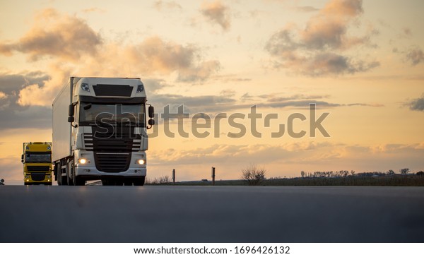 Truck rides highway against sunset\
background. International\
transportation.