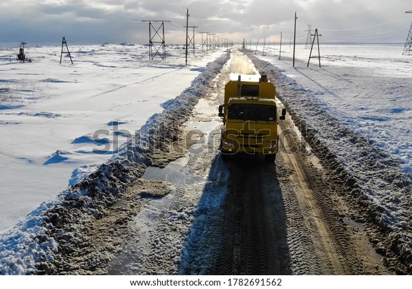 The truck\
rides on a winter road among the\
snow.