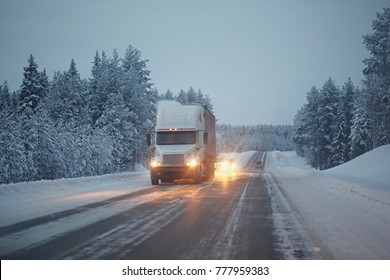 The Truck Rides On A Winter Snowy Road In The Forest. Dangerous Driving Conditions In Winter In Cloudy Weather.