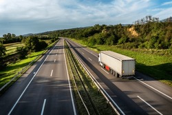 Truck With Semi-trailer Driving Along Highway On The Sunset Background. Goods Delivery By Roads. Services And Transport Logistics. Modern Lorry Transport Concept. Long Self-driving Lorries