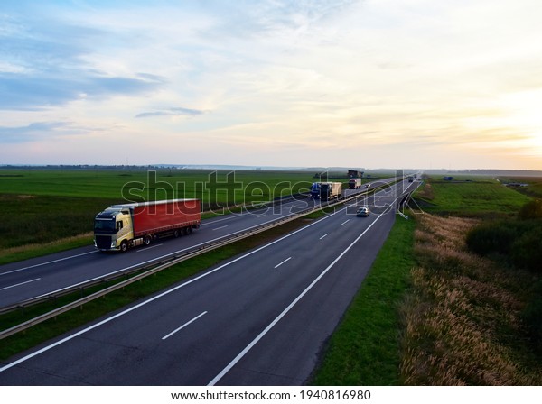 Truck with semi-trailer driving along\
highway on the sunset background. Goods delivery by roads. Services\
and Transport logistics.  Modern Lorry and traаfic transport\
concept. Long\
Self-driving