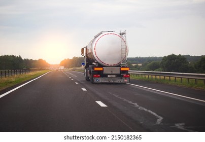 A truck with a semi-trailer transports a dangerous chemical cargo in a tank car on a highway against the background of a sunset. Sanctions in cargo transportation, capacity - Shutterstock ID 2150182365