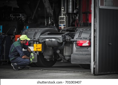 Truck Service Technician Job. Caucasian Truck Mechanic Checking On Semi Truck Tractor.