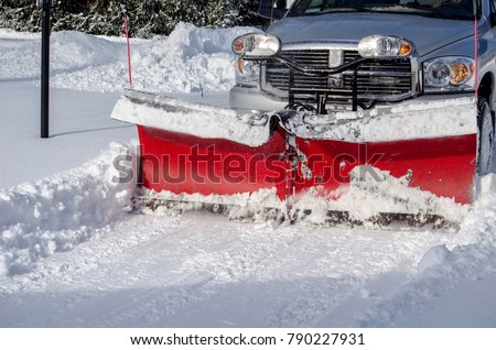 a truck with a snow blade clears snow after a storn  in a residential area in Michigan USA