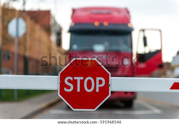 Truck standing\
at the barrier with a STOP\
sign.