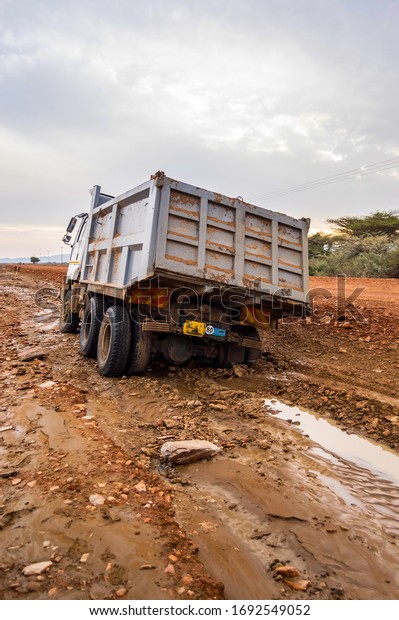 Truck stuck. The rear wheels are muddy. Mud road in\
the rift valley in Kenya