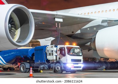 Truck With A Tank Of Kerosene Of Aviation Fuel Connected To The Fuel Tanks Of A Large Aircraft Airliner, Refueling Service Of A Night Flight