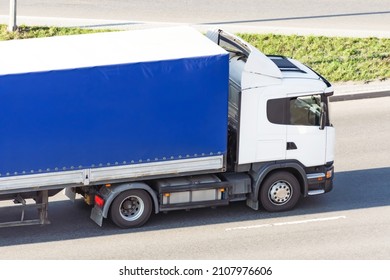 A Truck With A Tilt Trailer Rushes Along The Highway