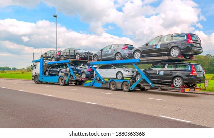 Truck trailer carrying several cars on a highway.