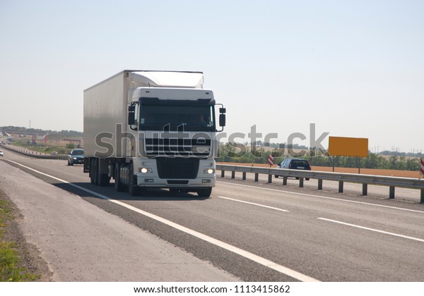 A truck\
with a trailer is driving along the\
highway
