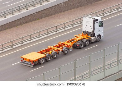 Truck With A Trailer And An Empty Orange Long Platform Rides In The City On The Highway