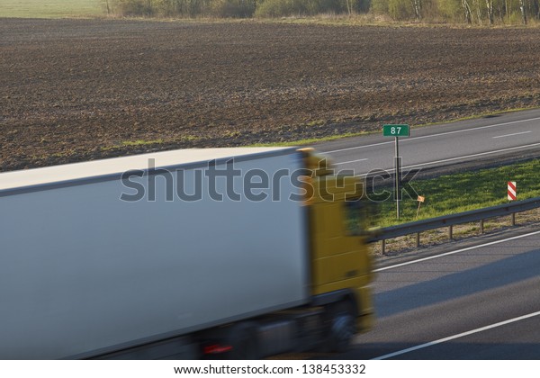 The truck\
with the trailer on the country\
highway