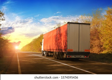 A Truck And A Trailer With Space For Text On The Countryside Road With An Autumn Forest Against A Night Sky With A Sunset