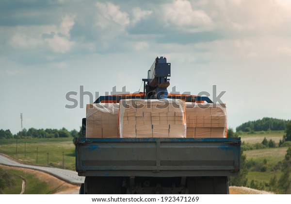 The truck is transporting bricks. A truck with\
bricks is driving on the\
road.