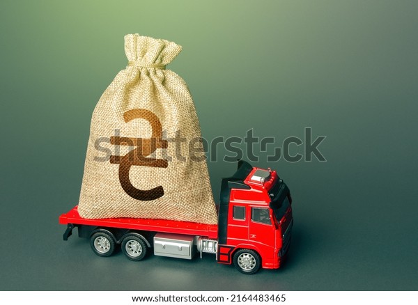 Truck with a ukrainian hryvnia money bag.\
Reparations. Financial and humanitarian aid. Loan or deposit.\
Compensation. High super income. Payment of taxes. Debt load.\
Donating money for\
recovery