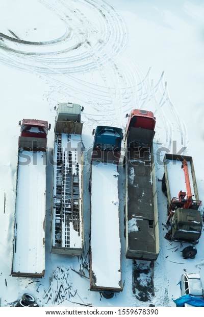 Truck under the\
snow. lorry covered with snow after snowfall. long trucks stand in\
a row top view. transportation concept. snow covered vehicles.\
aerial view with copy\
space