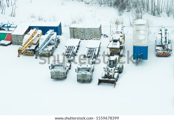 Truck under the\
snow. lorry covered with snow after snowfall. long trucks stand in\
a row top view. transportation concept. snow covered vehicles.\
aerial view with copy\
space