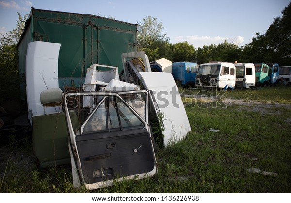 Truck or van\
doors, boot lids and seats awaiting to be used again. Half cut\
trucks, with faded colors. Awaiting dismantling or recycling, in a\
vehicle graveyard, Kozani,\
Greece.