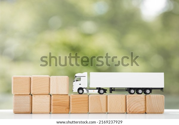 Truck with wooden cubes isolated on\
green summer background. Logistics and wholesale\
concept