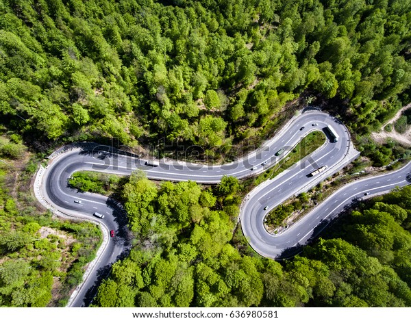 Trucks and cars on winding road trough the\
forest, Transfagarasan,\
Romania
