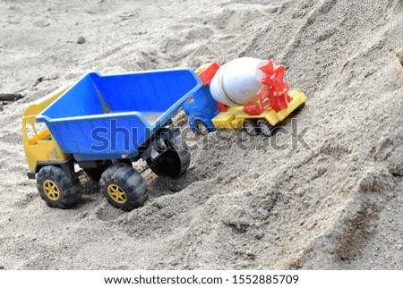 Trucks and cement mixers, children's toys on the pile of sand