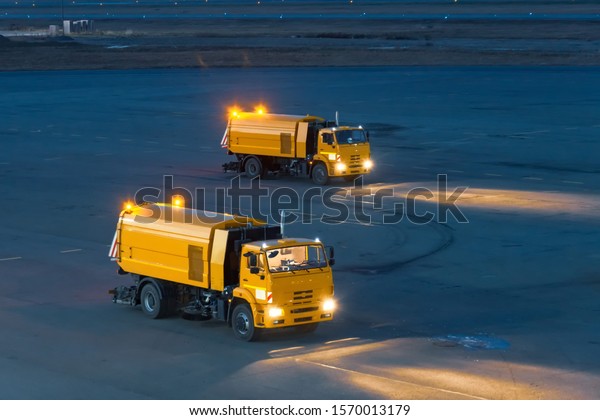 Trucks for cleaning garbage from roads at the\
airport, at night