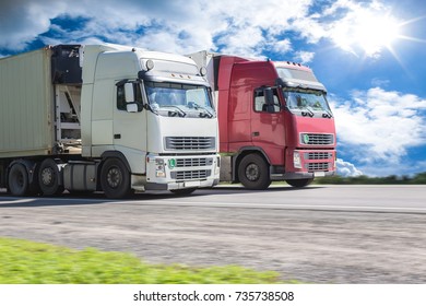Trucks moving along the highway against the background of the sunny cloudy sky