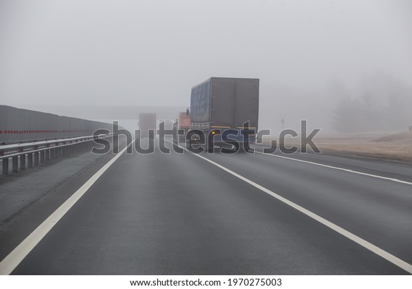 Trucks are\
moving in the fog on suburban\
highway