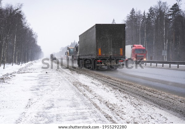 Trucks on the highway in dirty weather, Dangerous\
driving conditions in winter in cloudy weather. challenging winter\
weather driving conditions. dirt on the highway, transportation of\
goods in bad