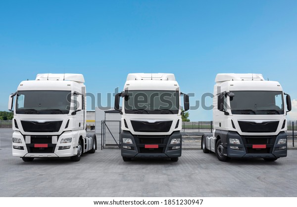 The trucks are parked in a row. Freight road\
transport, logistics and transport concept. Parking lot with trucks\
for delivery.