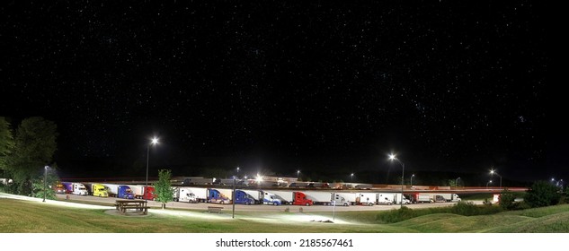 Trucks In Rest Area At Night. Truck Stop Wayside, Parked. Wide View With Copy Space And Lighted Foreground. Night Sky With Stars.