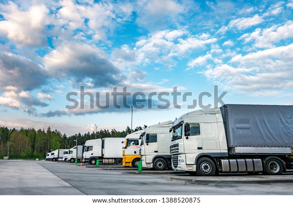 Trucks in a row with containers in\
the parking lot near forest , Logistic and Transport\
concept