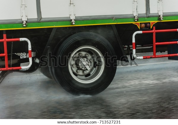 Trucks\
are running on the road at speed while it\
rains.
