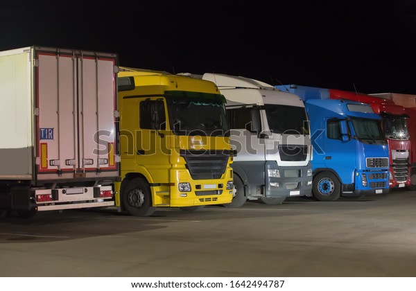 Trucks\
semitrailers in a lighted parking at\
night